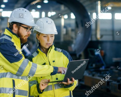 stock-photo-male-and-female-industrial-engineers-in-hard-hats-discuss-new-project-while-using-laptop-they-make-761907331